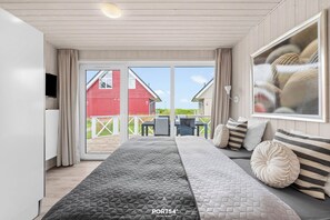 Ein Schlafzimmer mit einem großen Bett, einem Fernseher und Blick auf eine rote Scheune durch die Schiebetüren.