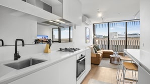 A modern kitchen with a built-in stove, a large sink, and a dining area with a bar stool. - Bright 1-bed Stay Near Crown Melbourne (Melbourne)