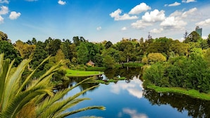 A serene park with a calm lake, lush greenery, and a distant building. - Bright 1-bed Stay Near Crown Melbourne (Melbourne)