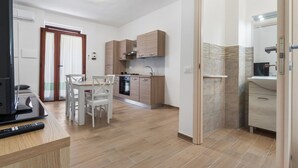 A modern kitchen with wooden cabinets, a dining table with chairs, and a built-in oven. - Apartment 'Casa Leone' with Air Conditioning (Teulada)