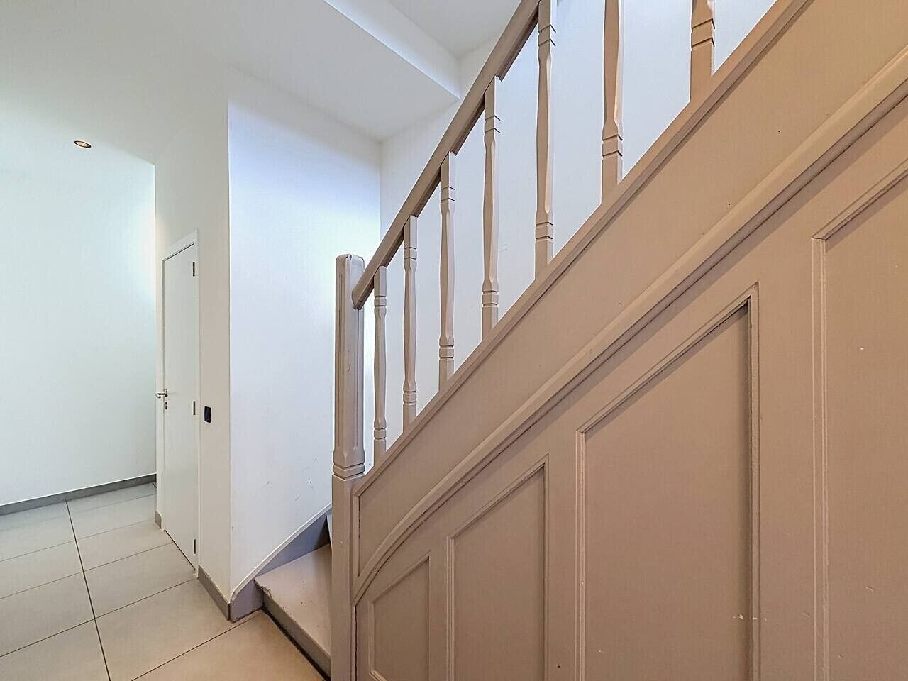 A staircase with wooden balusters and a beige wall.
