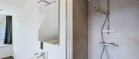 Un bagno moderno con uno specchio grande, un lavandino e una doccia.