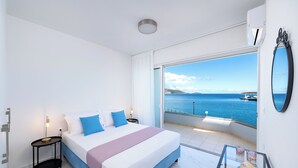 Un dormitorio con una cama grande, una mesita de noche, una mesa de vidrio y vistas al mar.