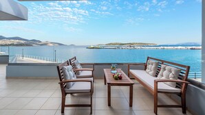 Un balcón con vistas al mar, una mesa con manzanas y dos sofás.