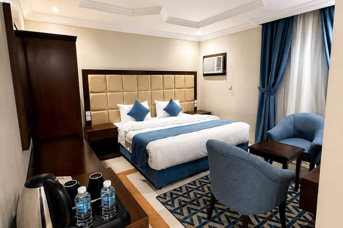 Una habitación de hotel con cama, escritorio, silla y cafetera.