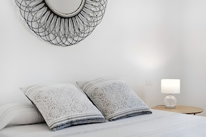A neatly made bed with patterned pillows, a wall-mounted abstract art piece, and a bedside table with a lamp. - Vencejo House – spacious accommodation for families or groups with mountain views (San Lorenzo)