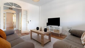 Een moderne woonkamer met een bank, een salontafel, een televisie en een boekenkast.