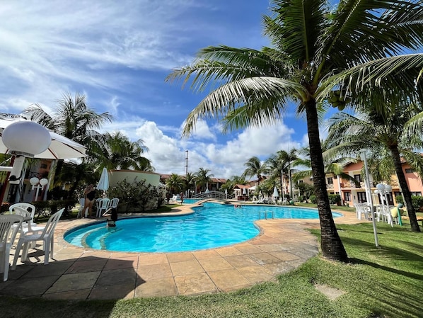 A swimming pool surrounded by palm trees and white chairs, with a clear blue sky above. - Dwelling place of Israel, Revelation 30 (Porto Seguro)