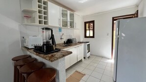 Eine Küche mit Kaffeemaschine, Herd, Kühlschrank und einem Fenster.