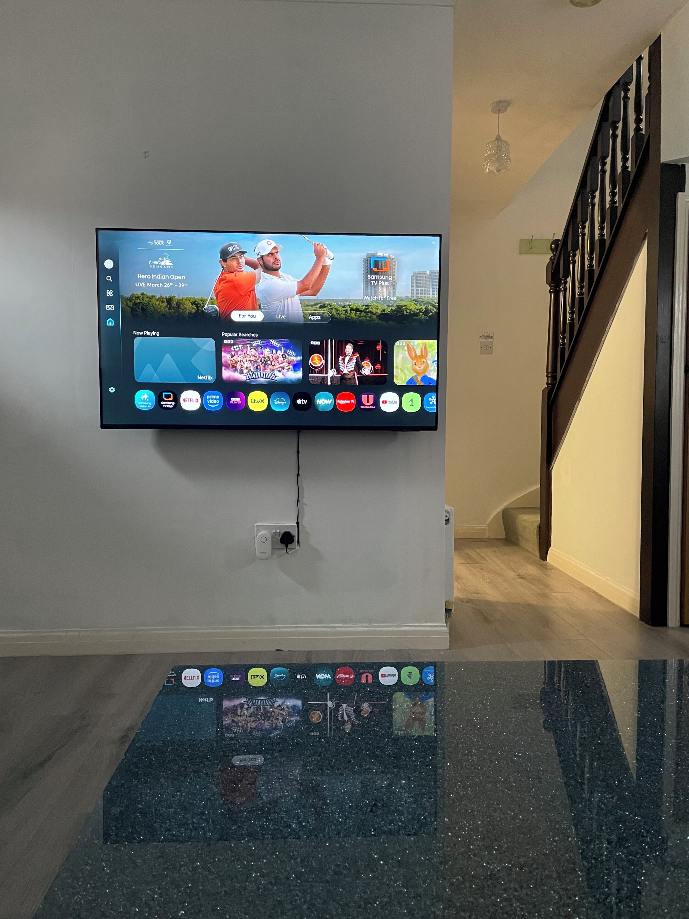 Ein wandmontierter Flachbildfernseher zeigt ein Sportevent und verschiedene Streaming-Apps.