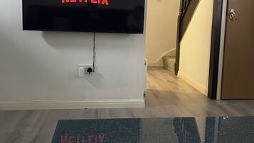 A wall-mounted television with the Netflix logo, a wooden staircase, and a door.