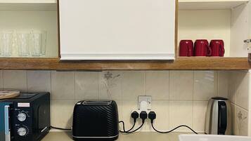 A kitchen with a toaster, a kettle, and a drawer with utensils.