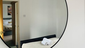 A circular mirror reflecting a bedroom with a bed, a door, and a hanging light fixture.