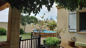 A pool area with a wooden deck, a small table, and potted plants. - Villa in Provence (Coudoux)