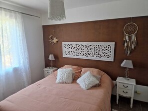 A bedroom with a bed, two nightstands, a decorative wall panel, and a dreamcatcher. - Villa in Provence (Coudoux)