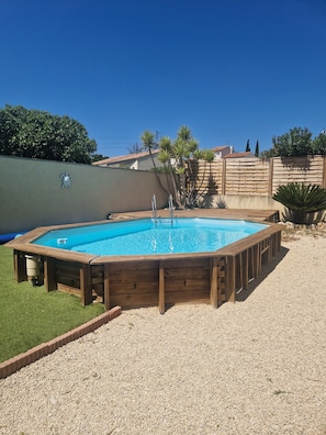 A rectangular swimming pool with a wooden deck, surrounded by a gravel area and a grassy lawn. - Villa in Provence (Coudoux)