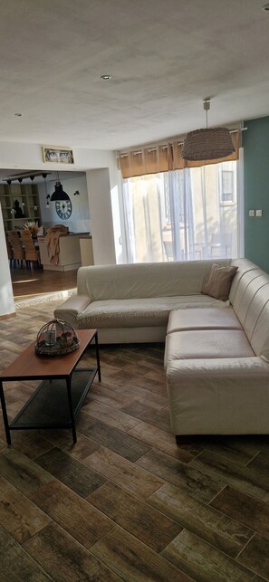 A living room with a sectional sofa, a coffee table, and a dining area in the background. - Villa in Provence (Coudoux)