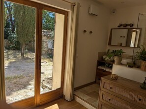 Habitación con puerta corrediza de vidrio que da a un espacio exterior, un armario de madera con cestas tejidas y un espejo en la pared.