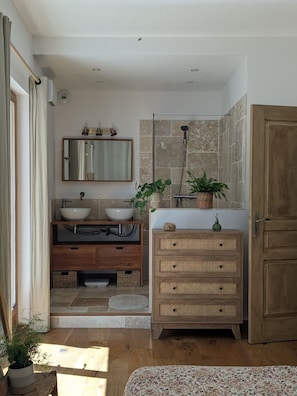 Un baño con lavamanos doble, espejo, ducha y armario de madera.