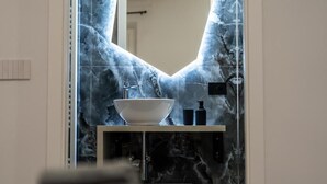 Un baño con un lavamanos blanco, un grifo y un dispensador de jabón.