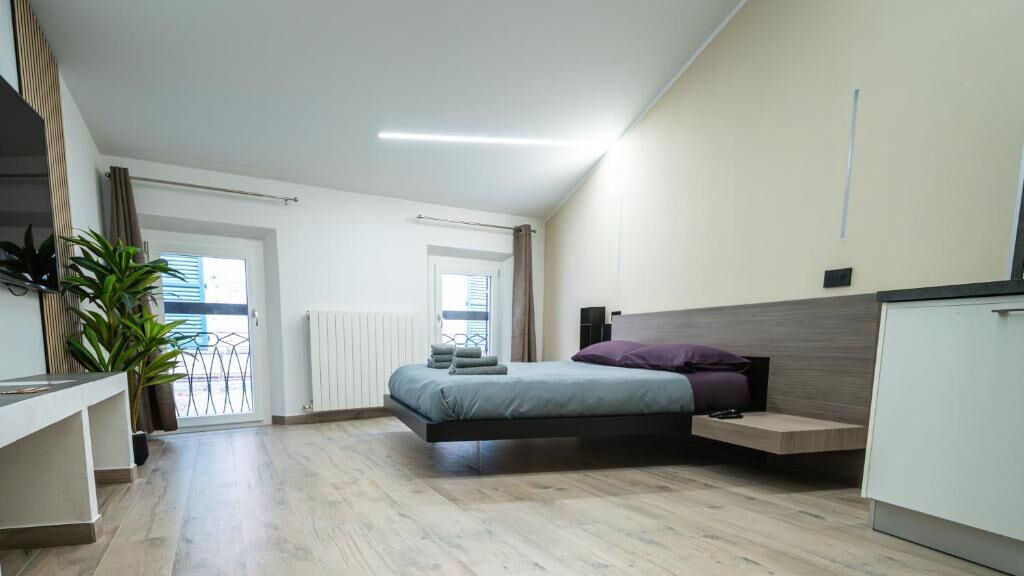 A modern bedroom with a bed, bedside table, and a potted plant.