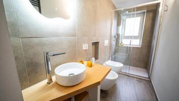 Une salle de bain moderne dotée d’un grand lavabo, de toilettes et d’un espace douche.