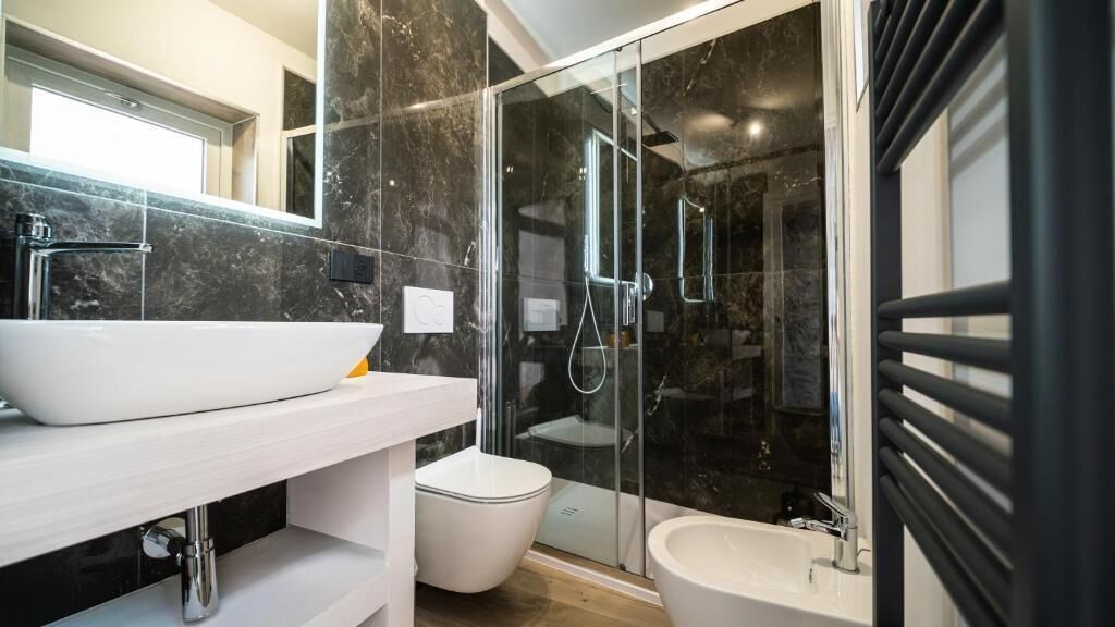 Un baño moderno con un lavabo blanco, cabina de ducha con vidrio y un bidé.