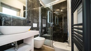 A modern bathroom with a white sink, a glass shower enclosure, and a bidet. - ESTENSIA Room&Suite (Ferrara)