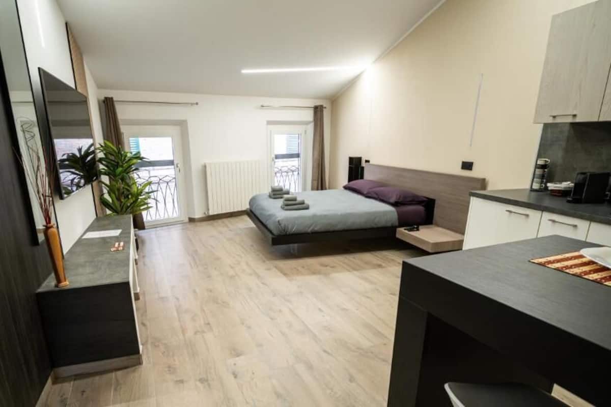 A modern bedroom with a bed, bedside tables, a desk, and a chair.
