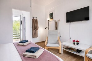 Ein Zimmer mit Bett, Stuhl, Fernseher und einem Fenster mit Blick.