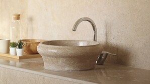 A bathroom with a stone sink, a wooden bowl, and two framed artworks on the wall. - Seven Stays Sidi Abd El-Rahman (El Alamein)