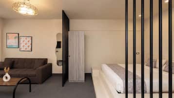 Una habitación de hotel moderna con un sofá, una cama, un espejo y una puerta que da a otra habitación.