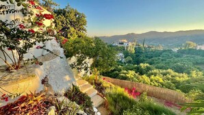 A garden with a white wall, steps, and a view of a cityscape with mountains. - La Casa Turquesa - Casa 1 (Frigiliana)