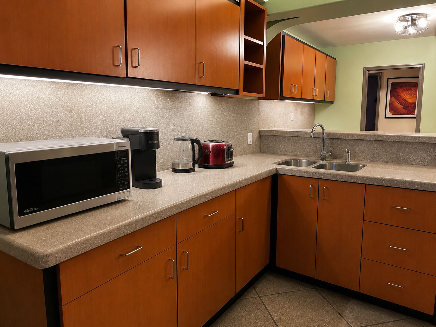 A kitchen with wooden cabinets, a microwave, a coffee maker, and a toaster.