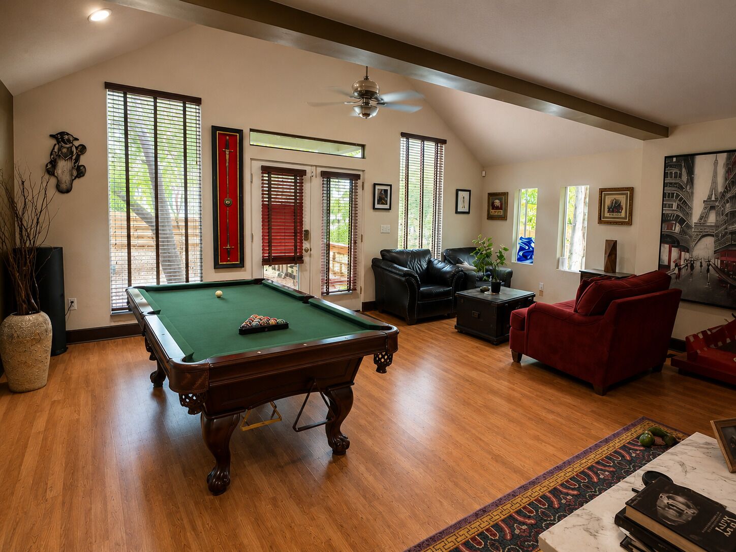 A pool table in a living room with a red sofa and a coffee table.