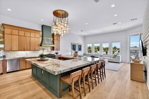 A modern kitchen with wooden cabinets, a marble island, and a large pendant light.