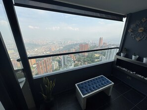 A balcony with a city view, a potted plant, a bench, and a wall clock. - Penthouse in the best view of Medellin (Medellín)