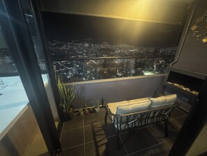 A balcony with a view of a city at night, a small table with a cushion, and a potted plant. - Penthouse in the best view of Medellin (Medellín)