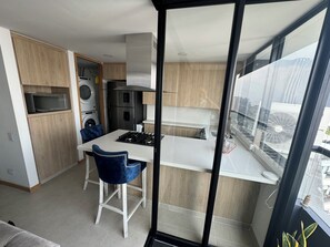 A modern kitchen with a dining area, built-in appliances, and a view through a glass door. - Penthouse in the best view of Medellin (Medellín)