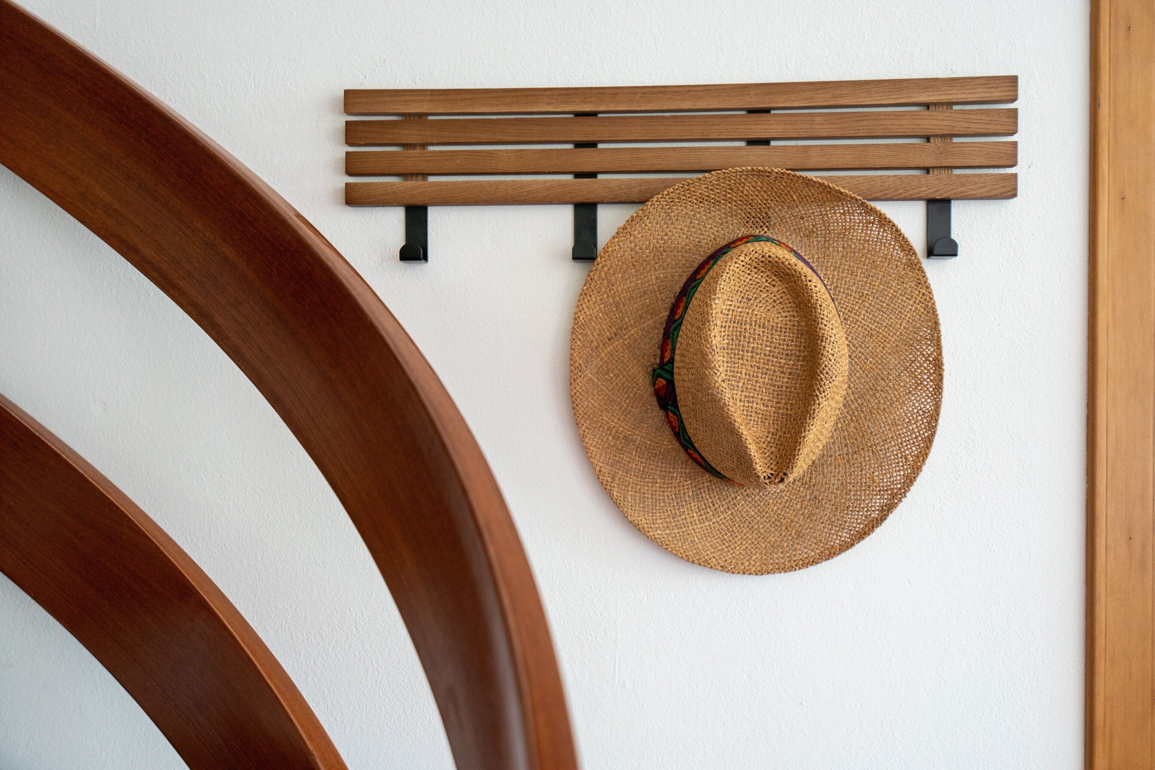 Een houten stoel en een hoed hangen aan een muur.