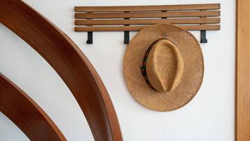 Een houten stoel en een hoed hangen aan een muur.