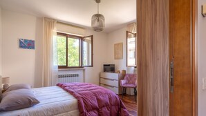 Una camera da letto con un letto, una cassettiera, una televisione e una sedia.