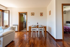 Un salon moderne avec un canapé, une table à manger et des chaises. On aperçoit une cuisine à l'arrière-plan.