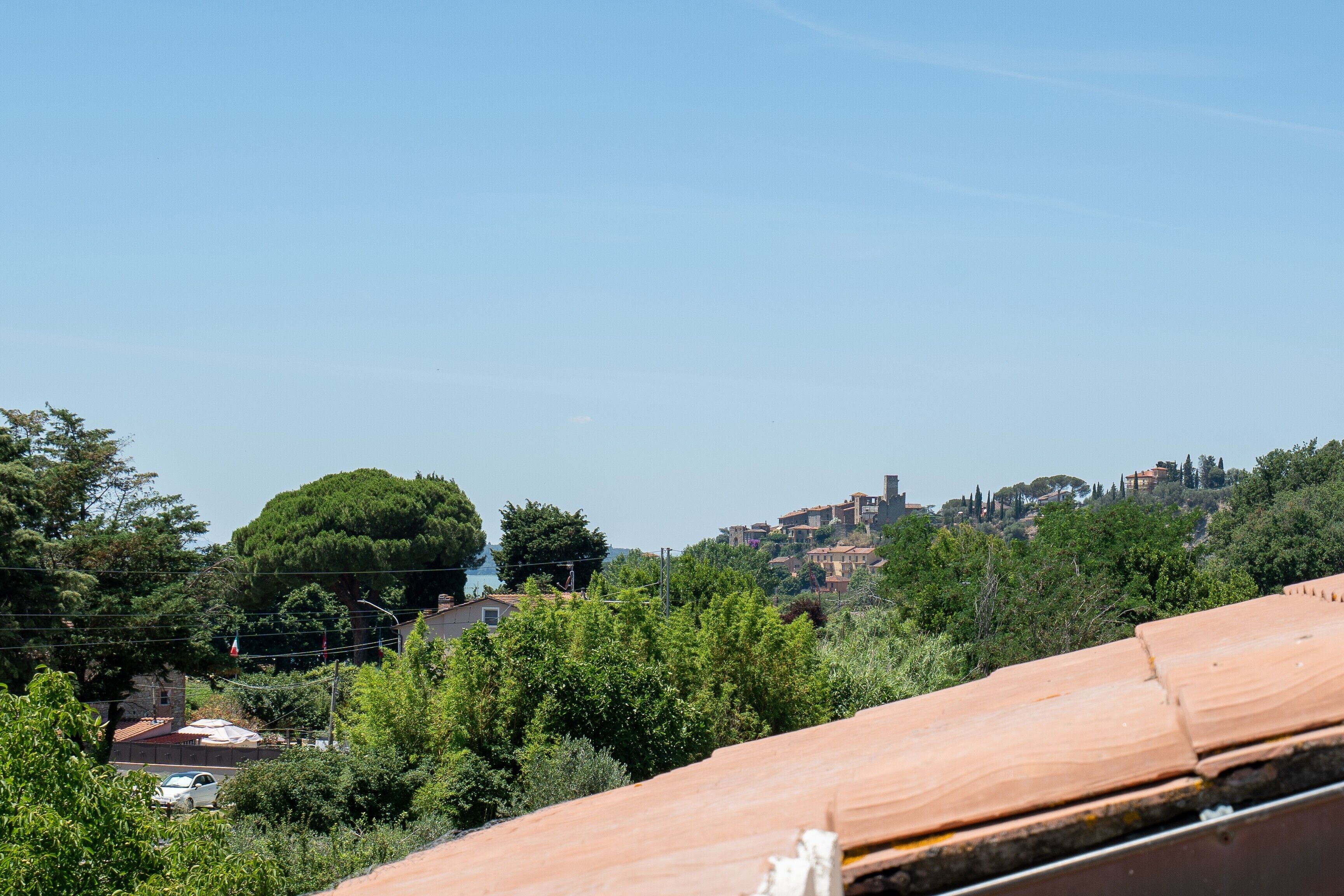 Une vue sur une colline, avec un ciel dégagé, des arbres et des bâtiments visibles au loin.