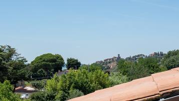 Une vue sur une colline, avec un ciel dégagé, des arbres et des bâtiments visibles au loin.