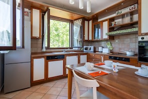 Une cuisine moderne avec des meubles en bois, un four à micro-ondes, une cuisinière et un coin repas comprenant une table et des chaises.