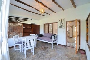 A room with a stone floor, white furniture, a woven ceiling light, and a view through a doorway. - Ascot Residence 2 Min Walk to the Beach (Watamu)