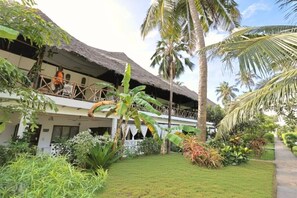 A resort with thatched-roof buildings, palm trees, and a well-maintained garden.