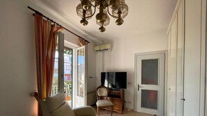 A living room with a sofa, a chair, a television, and a door leading to another room. - casa giusto ischia  (Ischia)
