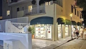 A building with a balcony, a storefront with awnings, and a paved sidewalk. - casa giusto ischia  (Ischia)